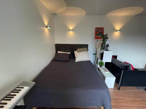 a bedroom with a large bed and a piano at The Prism ,studio on the top floor with a balcony in Neuilly-sur-Seine