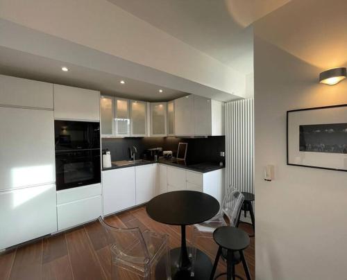 kuchnia z białymi szafkami oraz stołem i krzesłami w obiekcie The Prism ,studio on the top floor with a balcony w mieście Neuilly-sur-Seine