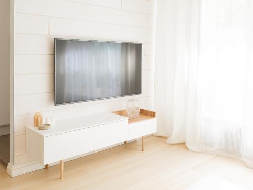 a white living room with a tv on a wall at Rosendahl - 75m2 Charming Two-story Apt next to the Best Beach and Scenic Park - Free Parking, Easy Check-in, Near Downtown in Tampere