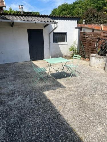 a green table in a yard next to a building at Chez Arthur in La Ferté-Saint-Aubin