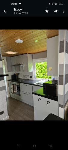 uma cozinha com armários brancos e um balcão preto em Glampavan em Haven Street