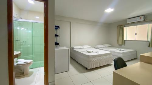 a room with two beds and a bathroom with a shower at CENTER PLAZA HOTEL in Cristalina