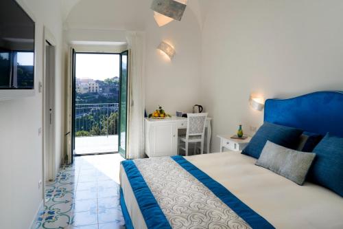 Schlafzimmer mit einem blauen und weißen Bett und einem Balkon in der Unterkunft Residence Villa Ruocco in Scala