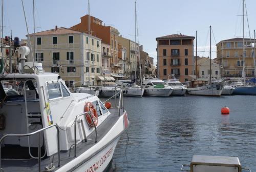 a white boat is docked in a harbor with buildings at A Punta Tegge il mare la spiaggia il tramonto in La Maddalena