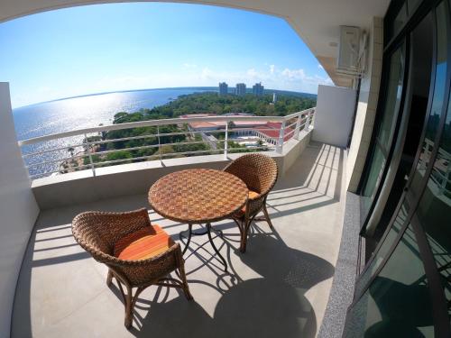 uma varanda com duas mesas e cadeiras e o oceano em Tropical Executive Hotel em Manaus