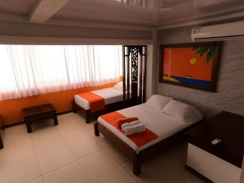 a bedroom with two beds and a tv on the wall at La Posada De Lulú in San Andrés