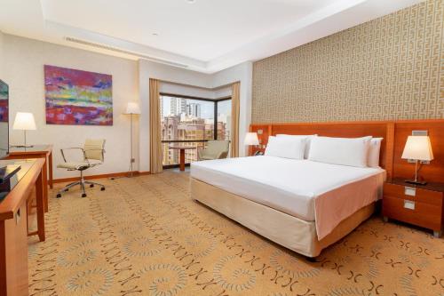 a hotel room with a large bed and a balcony at Holiday Inn - Suites Kuwait Salmiya by IHG in Kuwait