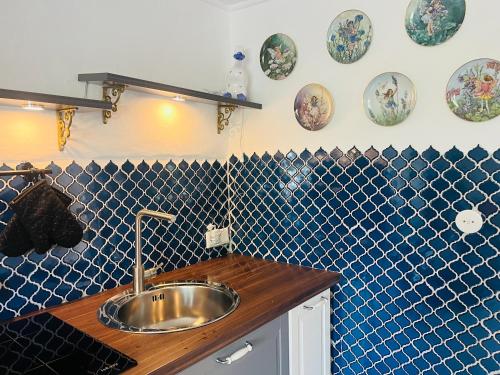 uma cozinha com um lavatório e uma parede de azulejos azuis em Charming historical farmhouse em Finning