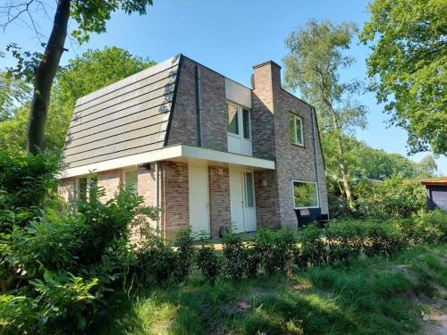a brick house with a gambrel roof at Boshuis Golfzicht "Wellness, Golf & Nature" in Oosterhout