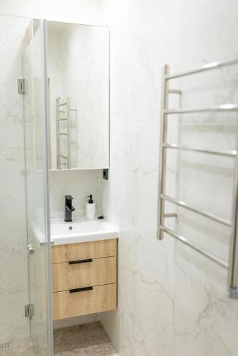 a white bathroom with a sink and a mirror at Windy City apartments in Liepāja