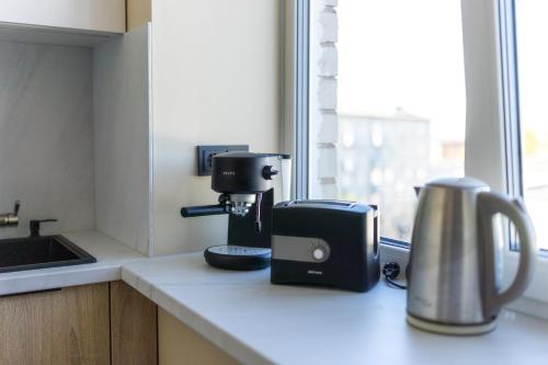 a kitchen counter with a coffee maker and a coffee pot at Windy City apartments in Liepāja