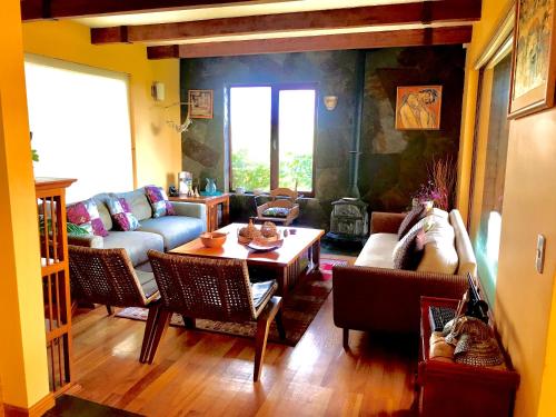 sala de estar con sofá y mesa en Suite abierta todo el año con vistas al campo, lago y ciudad, en Puerto Varas