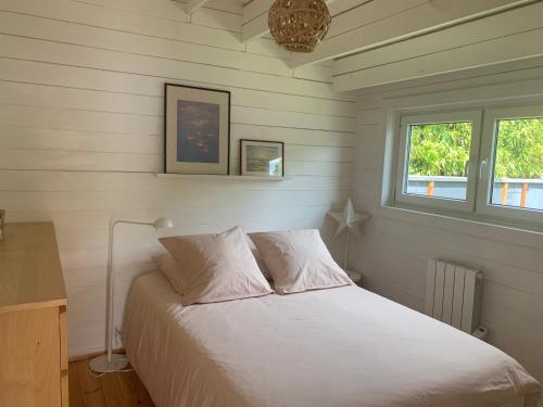 Schlafzimmer mit einem weißen Bett und einem Fenster in der Unterkunft Cottage Le Cerf-volant in Saint-Aubin-sur-Mer