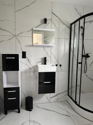 a white bathroom with a sink and a mirror at Domki u Karola in Rewal