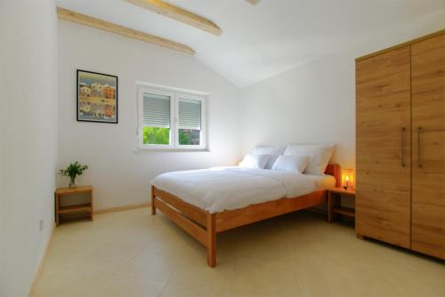 a white bedroom with a bed and a window at Apartmani Porat Sali in Sali