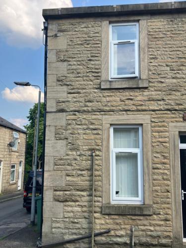 a stone house with two windows on a street at Entire central apartment which sleeps up to 6 in Ramsbottom