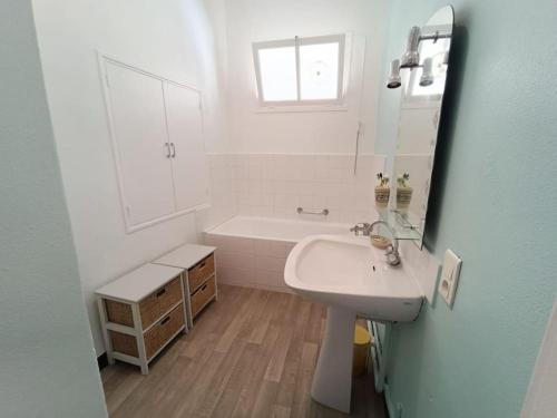 une salle de bain avec un lavabo, une baignoire et un miroir dans l'établissement Maison de village 8 couchages, à La Livinière