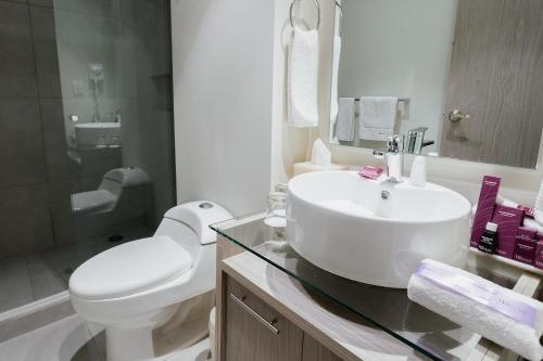 a white bathroom with a sink and a toilet at HS HOTSSON Acapulco Villas in Acapulco