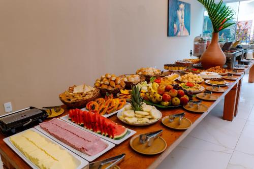 una mesa larga llena de diferentes tipos de alimentos en Miola Hotel, en Porto Seguro