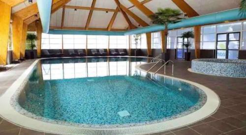 a large pool with blue water in a building at Traum Ferienhaus mit Dachterrasse am Veluwemeer in Hulshorst