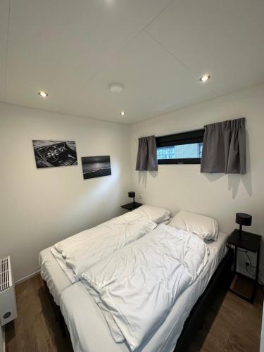 een slaapkamer met een bed met witte lakens en een raam bij Traum Ferienhaus mit Dachterrasse am Veluwemeer in Hulshorst