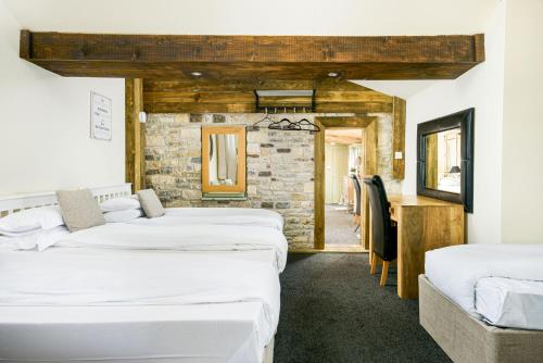 fila de camas en una habitación con pared de piedra en Bramley Barn near Bath + Hot tub en Siston