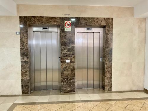 two silver elevators in a building with a no smoking sign at ChocolateCream Luxury in Bajamar
