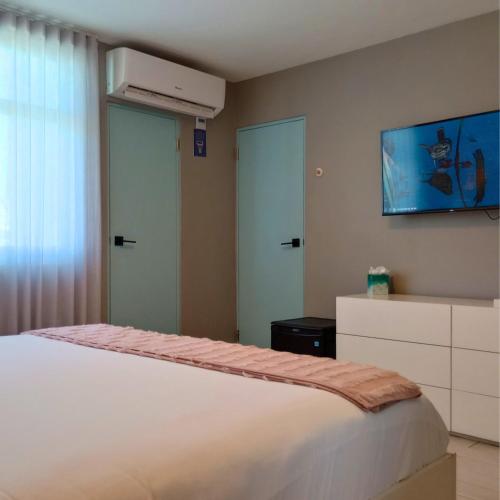 a bedroom with a white bed and a tv on the wall at Trópica Beach Hotel in San Juan
