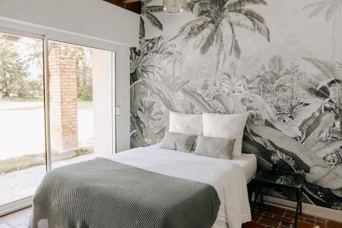 une chambre avec un lit avec un papier peint tropical dans l'établissement Maison de l'Ouest, à Biaudos