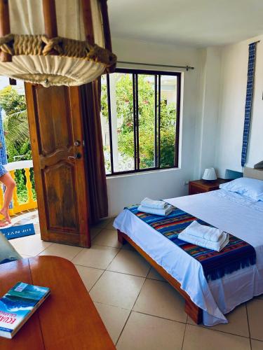 a bedroom with a bed and a table and a window at CASA MOSAICO in Puerto López