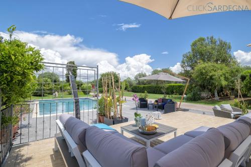 une terrasse avec des canapés et une piscine dans l'établissement ClickSardegna Villa Lavinia con piscina e accesso alla laguna Calich, à Casa Linari