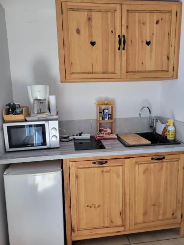 - une cuisine avec des placards en bois et un four micro-ondes dans l'établissement les marmottes, à Gérardmer