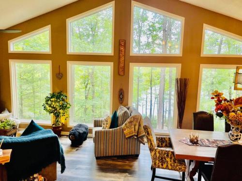 ein Wohnzimmer mit großen Fenstern sowie einem Tisch und Stühlen in der Unterkunft Stunning Lake front home with stunning decor in Mill Spring