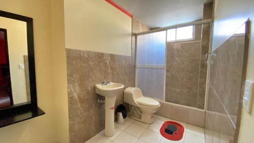 a bathroom with a toilet and a sink and a shower at Hostal y Complejo Recreacional La Playita de Monse in Otavalo