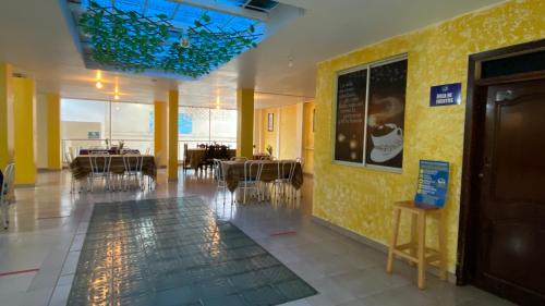 a restaurant with tables and chairs and a yellow wall at Hostal y Complejo Recreacional La Playita de Monse in Otavalo