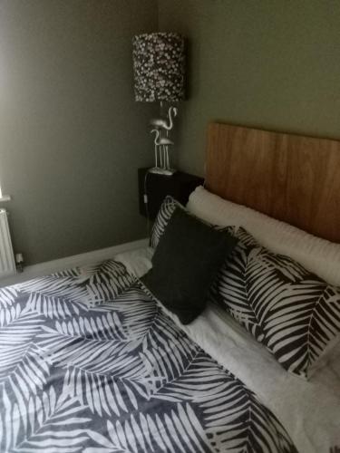 a bed with black and white sheets and pillows at DERBY in Derby