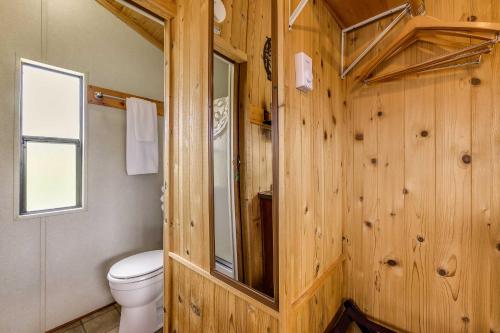 baño con aseo y pared de madera en Mayhill Tiny Home Vacation Rental with Covered Porch en Mayhill