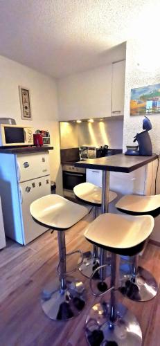- une cuisine avec des tables et des tabourets dans une pièce dans l'établissement studio à cent mètres de l'océan., à Seignosse