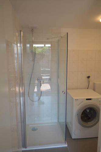 a shower in a bathroom with a washing machine at Beach Dream 3B in Petten