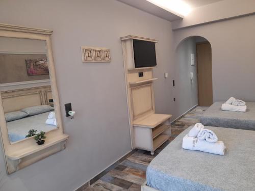 a room with two beds and a mirror at tomas & maria rooms in Nei Poroi