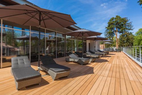 尤爾馬拉的住宿－NEW Rixwell Collection Seaside Hotel Jurmala，木甲板上的一排椅子和遮阳伞