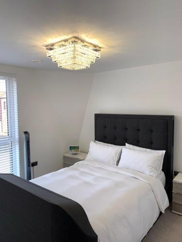 um quarto com uma grande cama branca e um lustre em G2 Luxury Rooms in a Shared House em Basildon