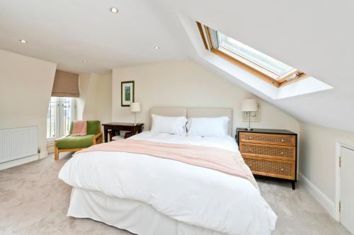 a bedroom with a large white bed and a skylight at Family Home near Clapham Common by UnderTheDoormat in London