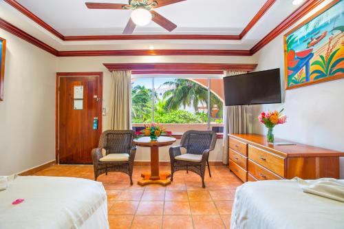 1 dormitorio con 2 camas, mesa y sillas en SunBreeze Hotel, en San Pedro