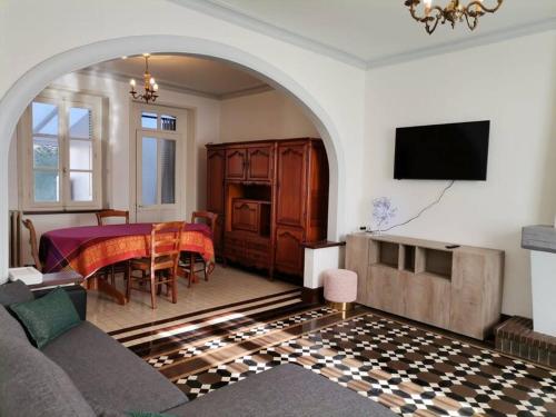 ein Wohnzimmer mit einem Tisch, einem Sofa und einem TV in der Unterkunft Grande maison de ville 120 m2 veranda et jardin. in Saint-Ouen