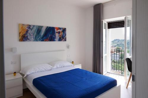 una camera da letto bianca con un letto blu e una finestra di B&B In Piazza a Mafalda