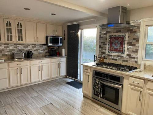 uma cozinha com armários brancos e um forno com placa de fogão em 4 Bedroom House-- perfect for families, near the beach! em Glen Cove