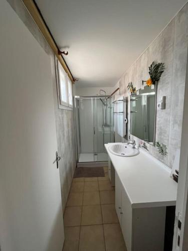 une salle de bain blanche avec un lavabo et une douche dans l'établissement Le Jean Bart, à Bréhal