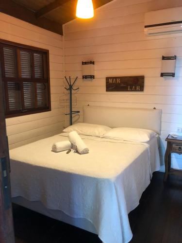 a bedroom with a white bed with towels on it at Pousada Aloha Beach House in Praia do Rosa