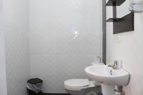 a white bathroom with a toilet and a sink at Hotel Villa del Rosario Nuevo in Melgar